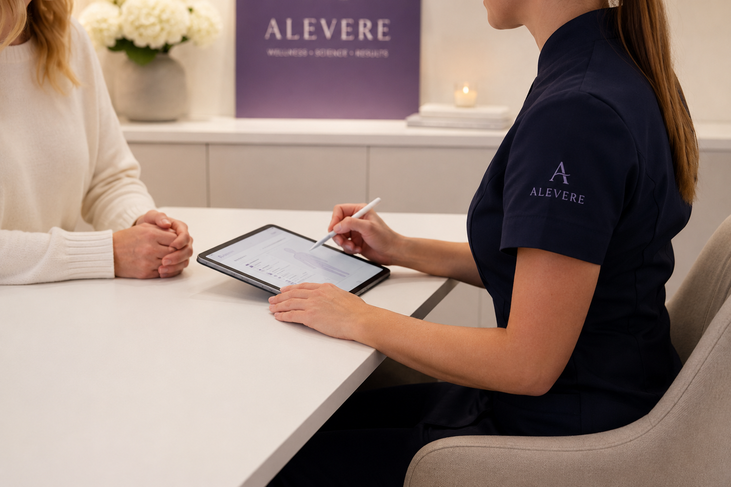Person in an Alevere shirt using a tablet with another person at a desk.