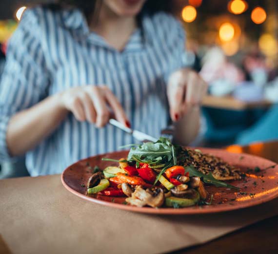 Person about to eat a plate of salad with various vegetables on a blurred background