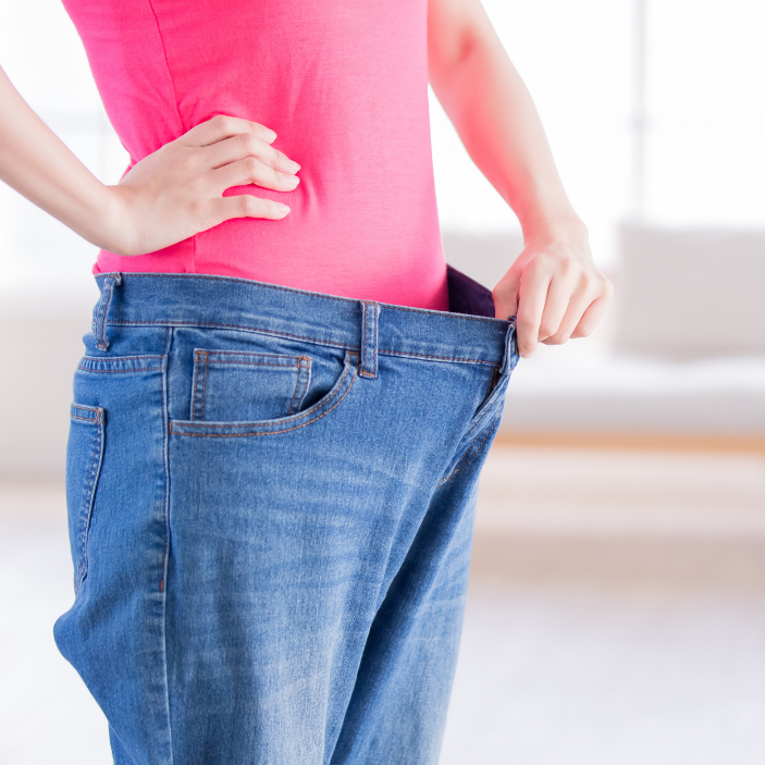 Person wearing oversized blue jeans and a pink shirt against a white background
