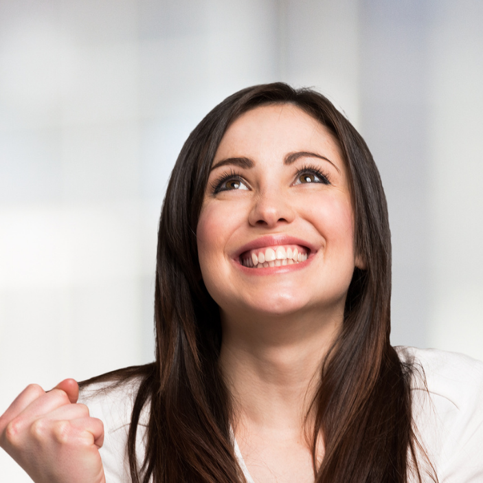 Woman with long brown hair smiling against a light background