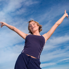 Woman with arms outstretched against a blue sky